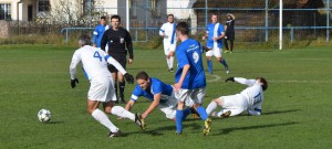 Marek Pěknic (uprostřed v modrém) padá po souboji s jedním z hráčů Lomu. V domácím derby se Plané nedařilo.